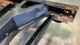 Professional installing the rear spare tire crossmember support piece for improved structural integrity.