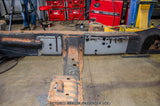 A heavy-duty rusted metal vehicle frame section, shown on a workshop floor with red welding equipment and tools in the background. Text overlay at the bottom reads 'PICTURED: RB9023R (PASSENGER SIDE)'.