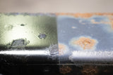 A close up look at a piece of frame rail with Rust Buster Rust Converter & Primer Spray Paint RB9917 sprayed to treat the left side, and the right side left untreated.
